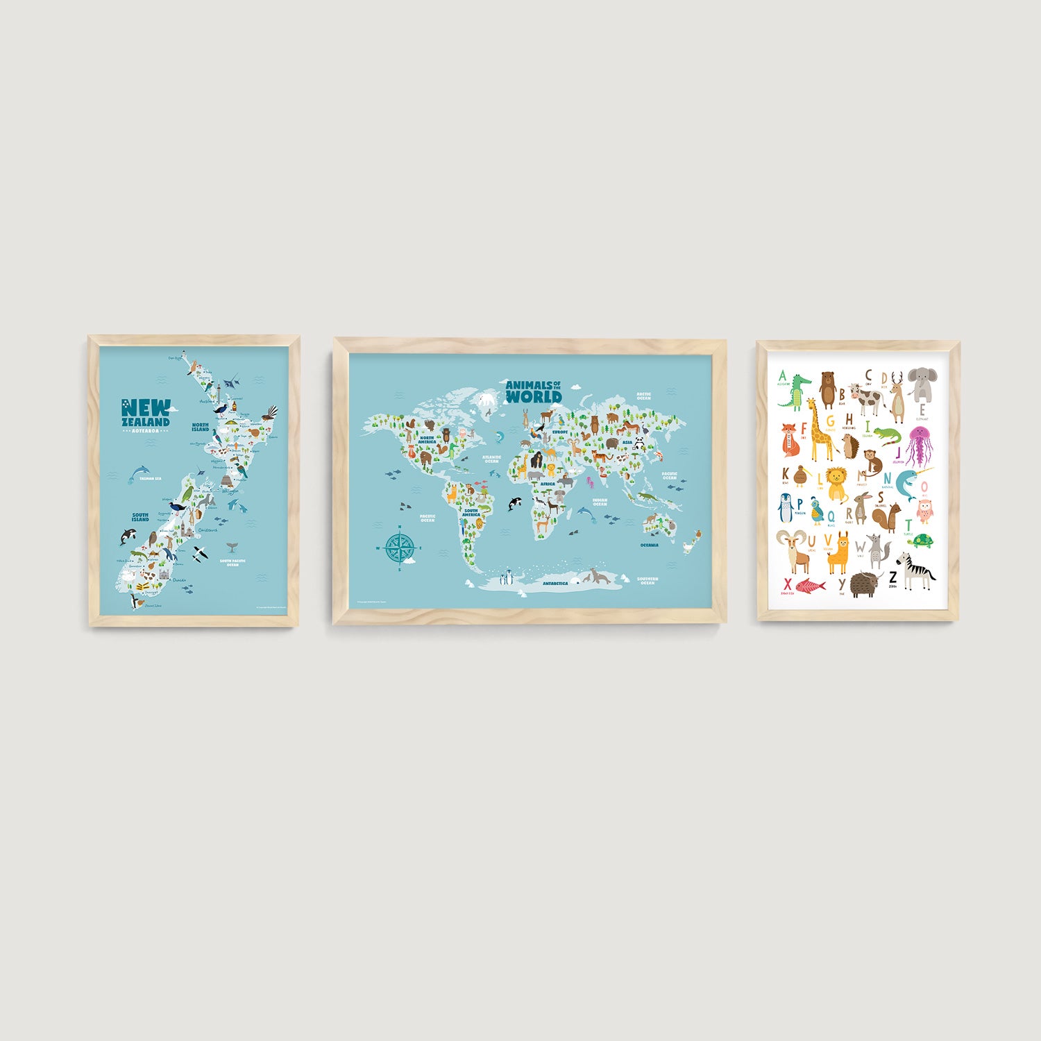 Three framed nursery and kids wall art prints of a world map with animal, a New Zealand map with animals and landmarks and alphabet chart on a light gray wall decor  - Bluish Nest Art Studio