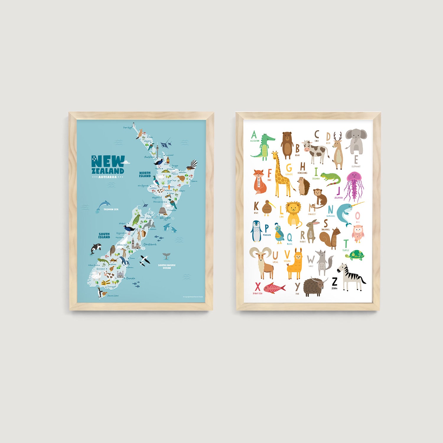 Two framed kids and nursery wall art prints on a wall, one with an animal map of New Zealand and the other an animal alphabet chart - Bluish Nest Art Studio