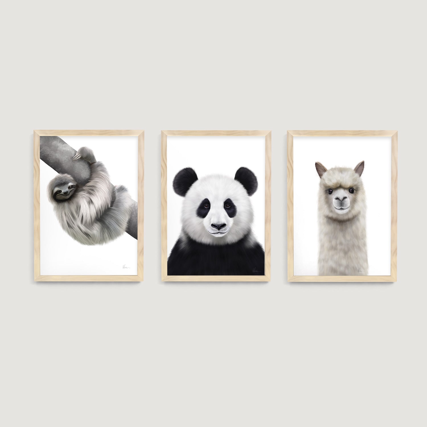 Three framed baby and children prints of a sloth, panda, and alpaca on a white wall decor  - Bluish Nest Art Studio
