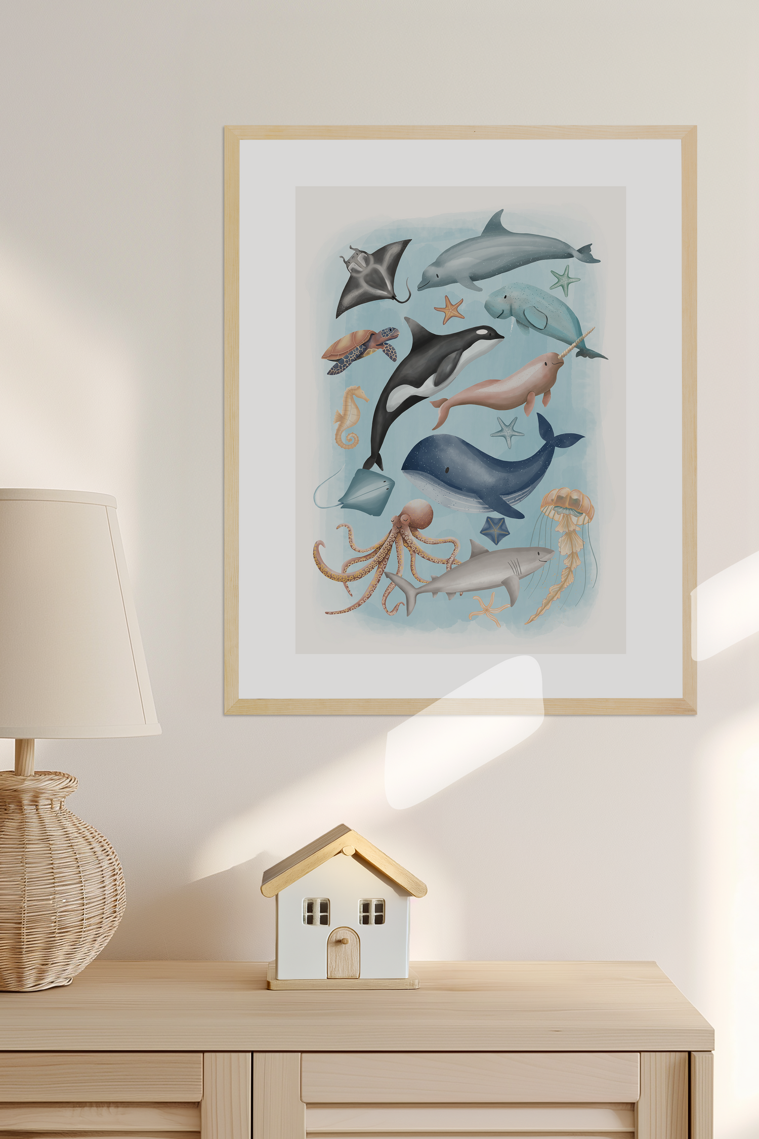 Framed kids art of marine life on a wall above a wooden cabinet with decorative items  - Bluish Nest Art Studio