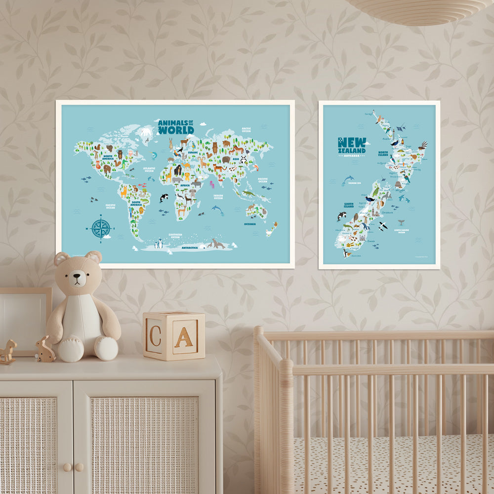 One animal world map and one New Zealand map in frames on a wall above a crib and cabinet with a teddy bear and wooden blocks. Nursery room decor - Bluish Nest Art Studio