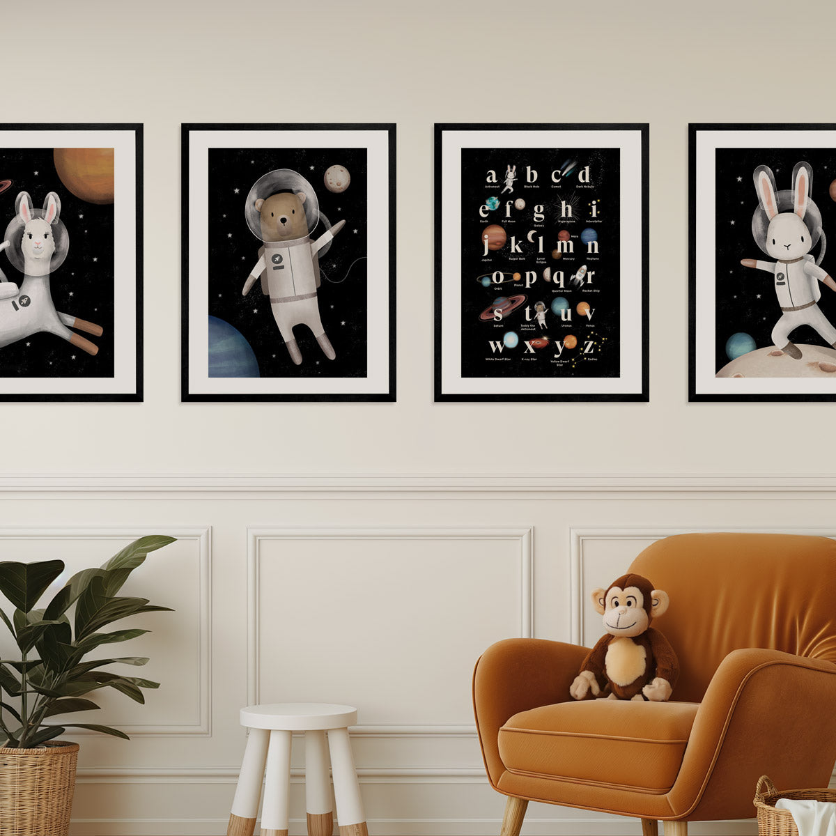 Four framed baby and kids art prints on a wall of Space llama, bear, rabbit and alphabets above an orange armchair with a monkey plush toy - Bluish Nest Art Studio