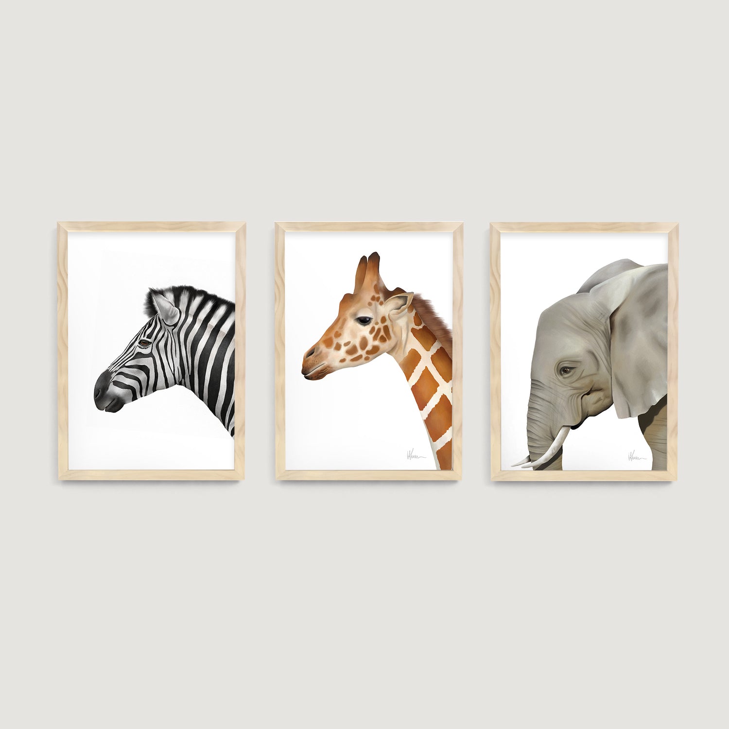 Three framed kids and nursery wall art  prints of a safari zebra, giraffe, and elephant on a white wall - Bluish Nest Art Studio