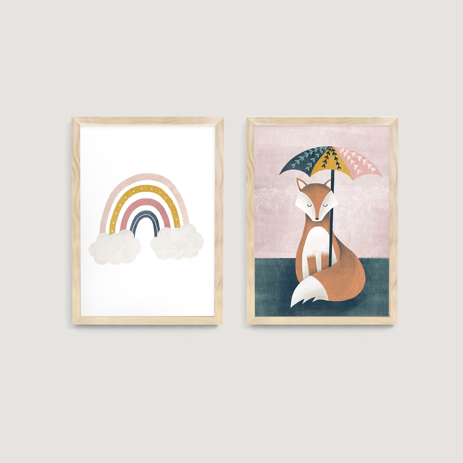 Two framed nursery and kids wall art prints on a wall, one with a rainbow and clouds, the other with a fox under an umbrella  - Bluish Nest Art Studio