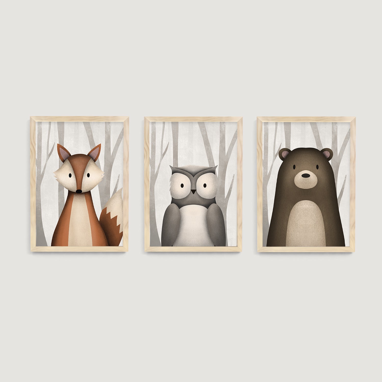 Three framed children and baby wall art prints of a fox, owl, and bear in a forest setting on a light gray wall - Bluish Nest Art Studio