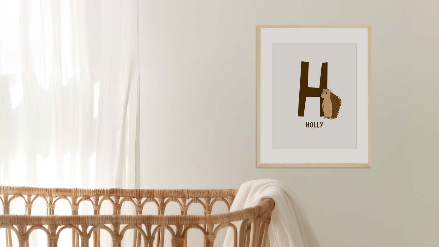 Personalised name nursery framed art print with a letter 'H' and name 'Holly' on a wall next to a wicker crib - Bluish Nest Art Studio